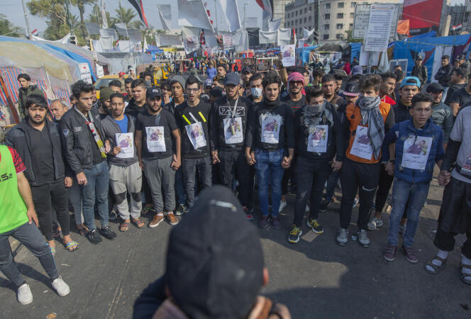 Des manifestants rassemblés place Tharir, le 26 décembre. Sur leur poitrine, le portrait d’un protestataire mort.