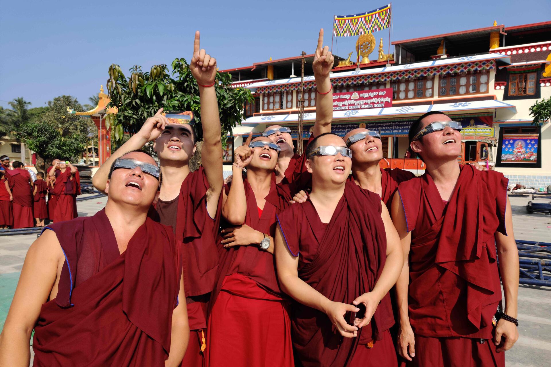 Des moines observent l’éclipse depuis leur monastère de Teginkoppa (Inde), le 26 décembre 2019.