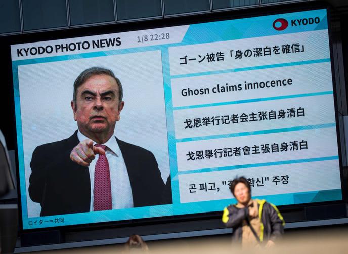 Un piéton passe devant un grand écran montrant une émission d’actualités mettant en vedette l’ancien chef de Nissan Carlos Ghosn à Tokyo le 9 janvier 2020. Le ministre japonais de la Justice a exhorté Carlos Ghosn à revenir et à plaider sa cause devant le tribunal, après que l’ancien magnat de l’automobile a fuit au Liban.