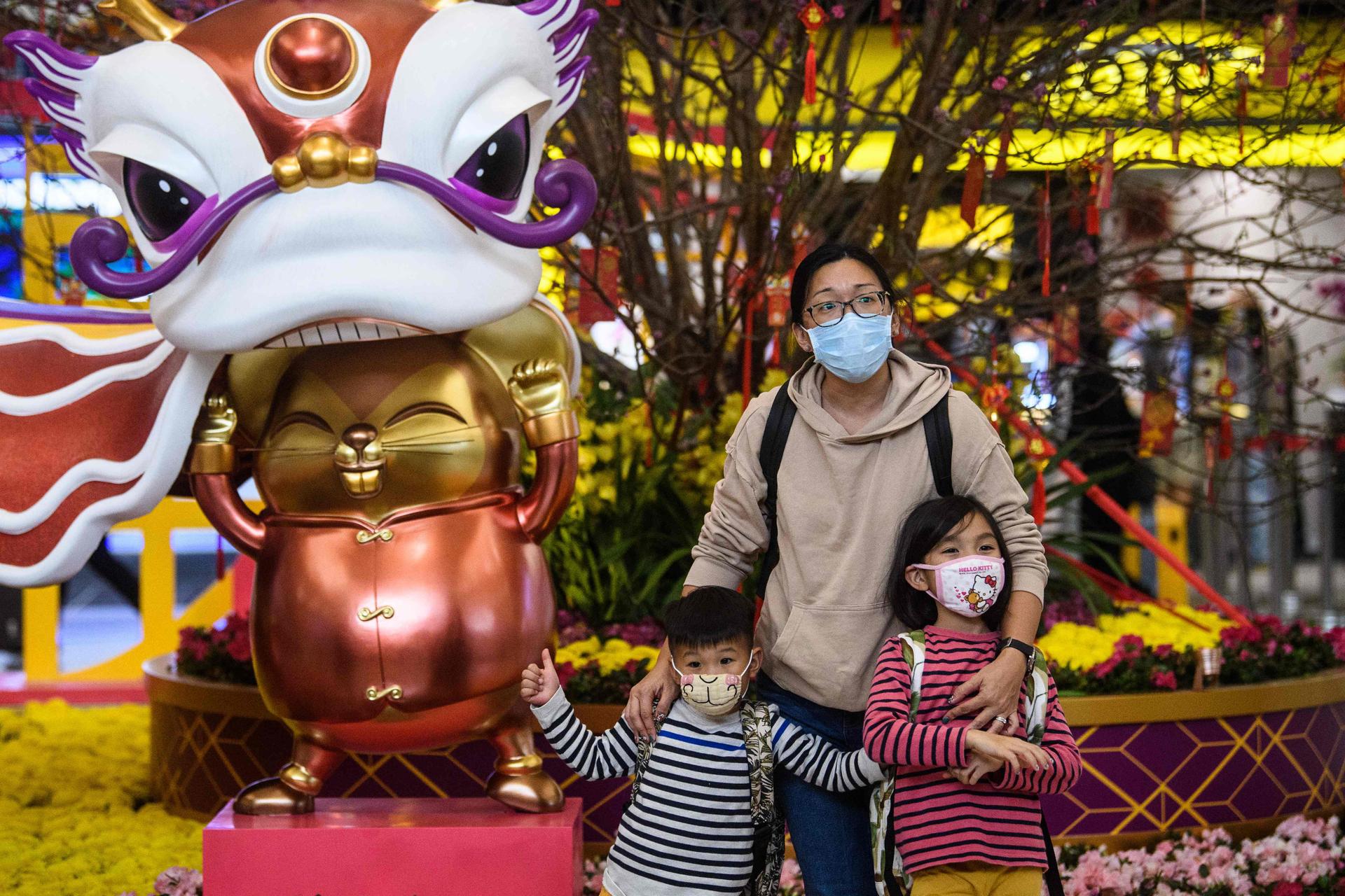 Des voyageurs prennent la pose en famille devant l’installation en vue du Nouvel An à l’aéroport international de Hongkong.
