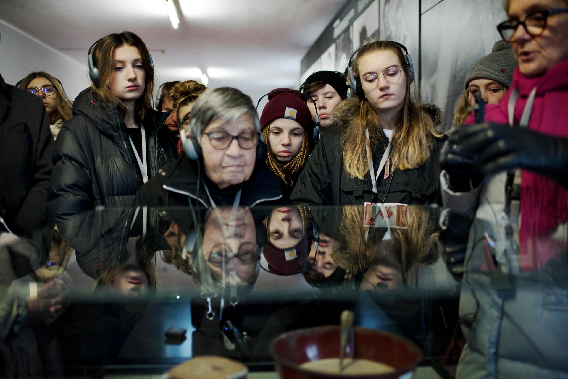 Les élèves et Ginette Kolinka regardent les écuelles dans lesquelles les déportés mangeaient, à Auschwitz. Les rations étaient calculées par les nazis pour une survie entre un et six mois.