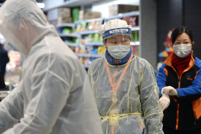 Un membre du personnel d’un supermarché portant un masque de protection et une combinaison à Wuhan, le 10 février.