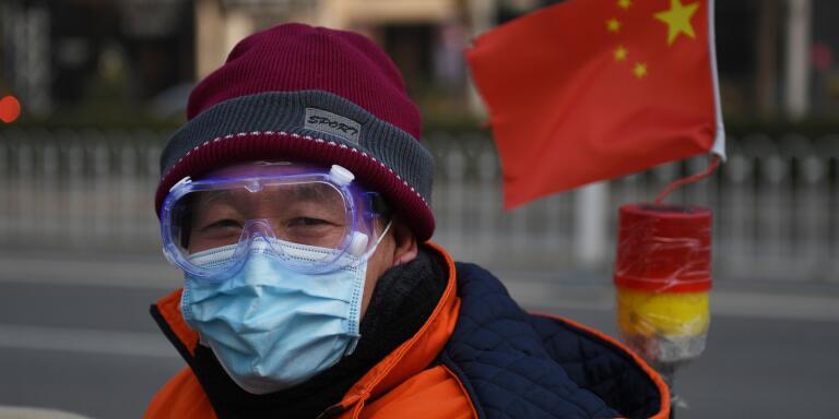 A cleaner wears a mask and goggles as he commutes on a street in Beijing on February 11, 2020. The death toll from a new coronavirus outbreak surged past 1,000 on February 11 as the World Health Organization warned infected people who have not travelled to China could be the spark for a 