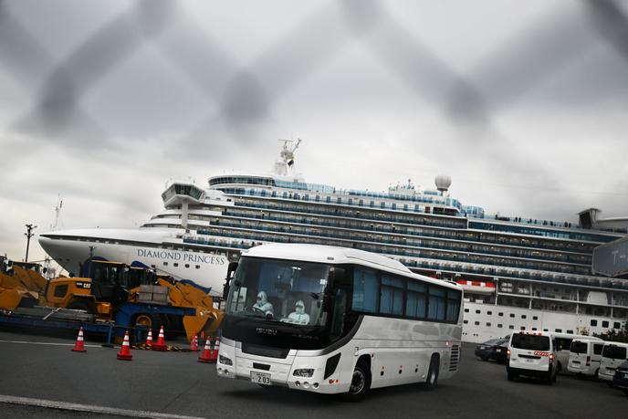 Des hommes en combinaison quittent le « Diamond Princess », où sont confinées 3600 personnes, dans le port de Yokohama, près de Tokyo, le 14 février 2020.