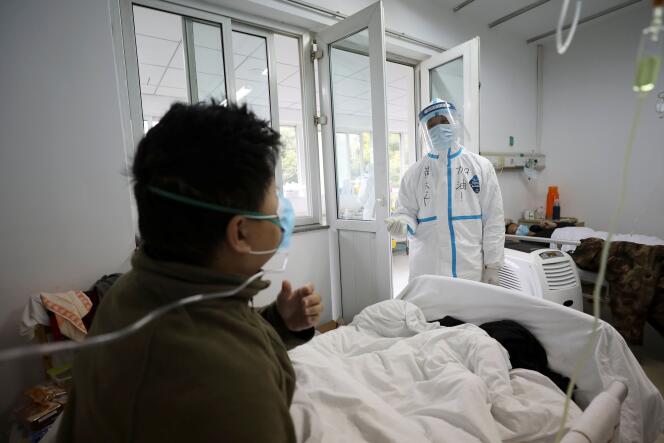 Un employé médical assiste un patient dans un service isolé de l’hôpital de Wuhan, le 13 février.