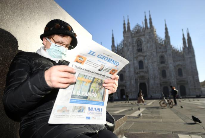 Un homme lit le journal devant la cathédrale de Milan, lundi 24 février.