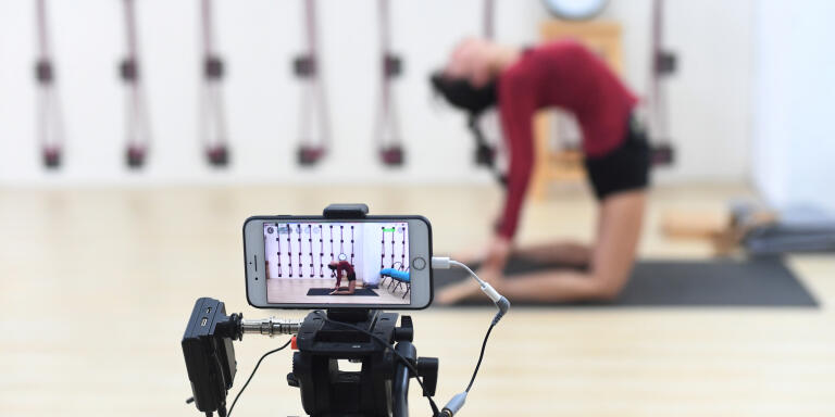 An instructor does a live broadcast of her yoga lesson with a mobile phone as the yoga academy offers free online classes following the outbreak of the novel coronavirus, in Guangzhou, Guangdong province, China February 7, 2020. Picture taken February 7, 2020. cnsphoto via REUTERS   ATTENTION EDITORS - THIS IMAGE WAS PROVIDED BY A THIRD PARTY. CHINA OUT. - RC26WE90MNZM