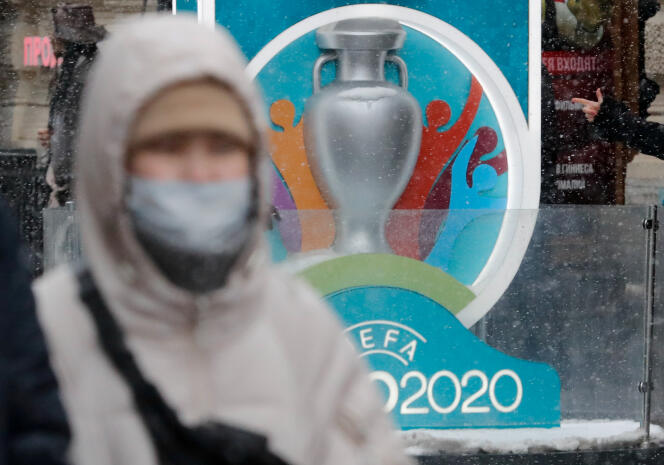 Un homme portant un masque de protection devant une affiche de l’Euro 2020 à Saint-Pétersbourg, l’une des douze villes hôtes.