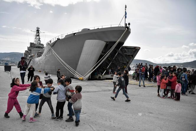 Des enfants jouent devant le navire qui accueille les réfugiés arrivés dans le port de Mytilène, sur l’île de Lesbos, le 7 mars.