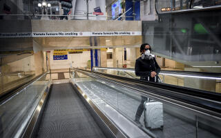 A woman wears a mask as she stands on an escalator inside Central train station, in Milan, Italy, Sunday, March 8, 2020. Italy announced a sweeping quarantine early Sunday for its northern regions, igniting travel chaos as it restricted the movements of a quarter of its population in a bid to halt the new coronavirus' relentless march across Europe. (Claudio Furlan/LaPresse via AP)