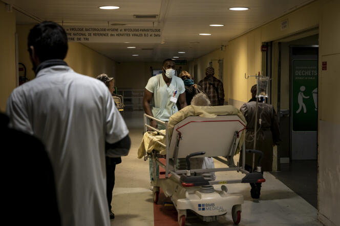 Un employé de l'hôpital Henri-Mondor, à Créteil, porte un masque alors qu'il transporte un patient âgé, le 6 mars 2020.