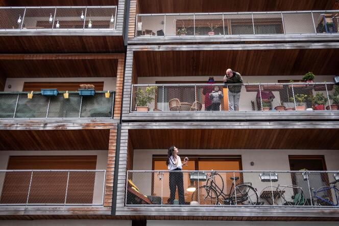 Des voisins échangent quelques mots depuis leurs balcons, un verre à la main, à Paris, le 20 mars 2020.