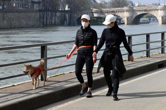 Deux femmes portant un masque protecteur marchent le long des rives vides de la Seine, au 4e jour de confinement, à Paris, le 20 mars.