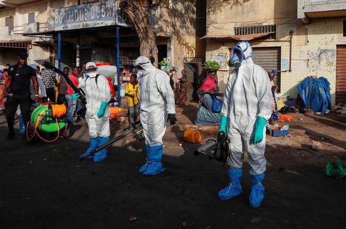 Les membres des services d’hygiène désinfectent les abords d’un marché pour tenter d’arrêter la propagation du coronavirus, à Dakar (Sénégal), le 22 mars.