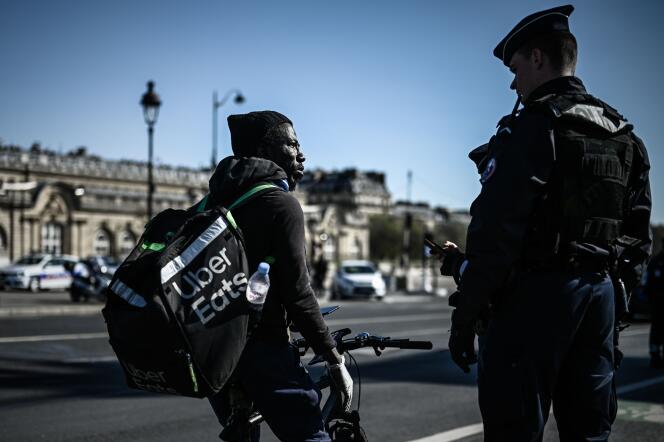 Un officier de police contrôle un livreur Uber Eats, lors du confinement français de mars 2020, à Paris.