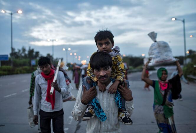 Un travailleur migrant porte son fils sur la route de son village à New Delhi, le 26 mars.
