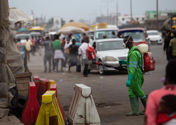 Désinfection des rues du marché à Accra, devant une file de VTC, le 23 mars 2020.