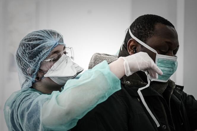 Une soignante équipe d’un masque un patient soupçonné d’être atteint du Covid-19, le 27 mars, à Paris.
