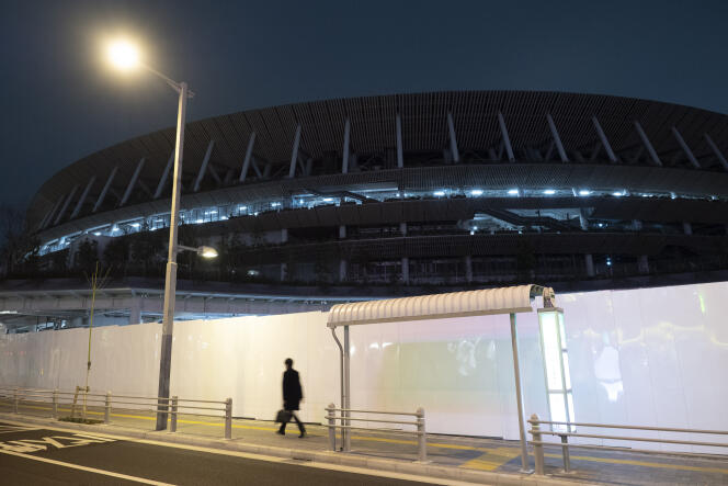 Un homme marche le long du mur du nouveau stade olympique national, à Tokyo, le 30 mars.