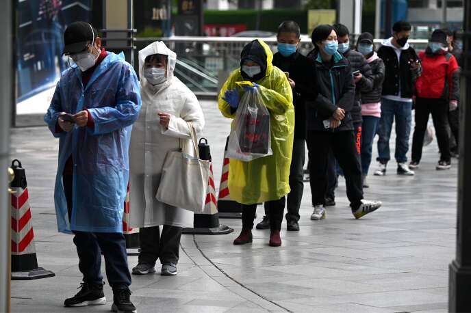 Des gens portant des masques font la queue à l’entrée d’un supermarché de Wuhan, en Chine, le  30 mars 2020.