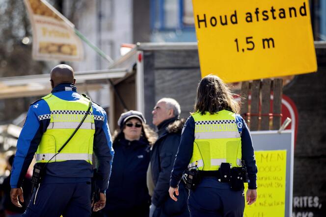 La police néerlandaise effectue des contrôles du respect des mesures de distanciation sociale, à Amsterdam, le 31 mars. Le panneau rappelle la consigne de se tenir à 1,5 m au minimun d’une autre personne.