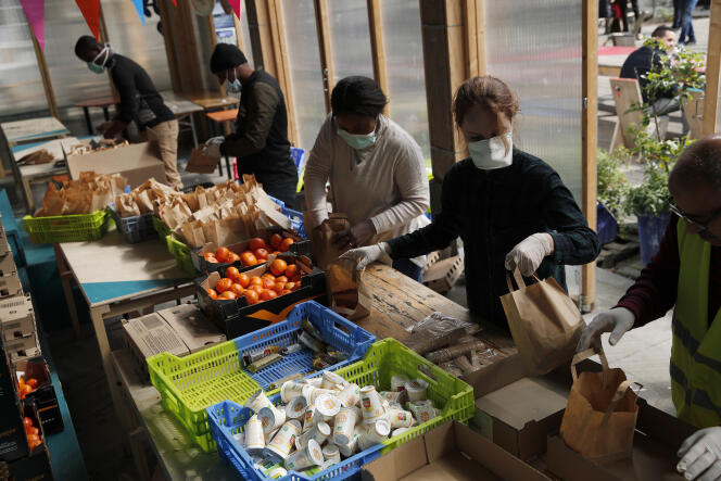 Des bénévoles de l’association Aurore préparent des repas à distribuer à des sans-abri et à des migrants, le 2 avril à Paris.