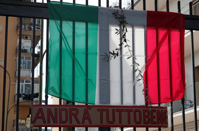 Un rameau accroché au drapeau italien, accompagné du message « Tout ira bien », à Naples, le 5 avril 2020, jour du dimanche des rameaux dans la liturgie catholique.