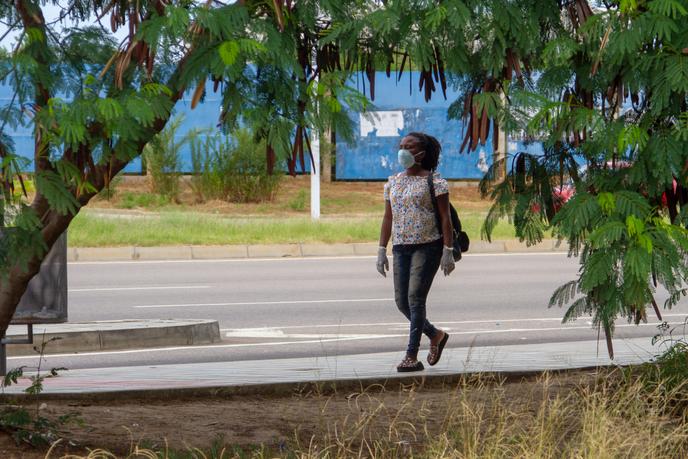 Une femme marche dans une rue de Luanda avec un masque et des gants, le 27 mars 2020.