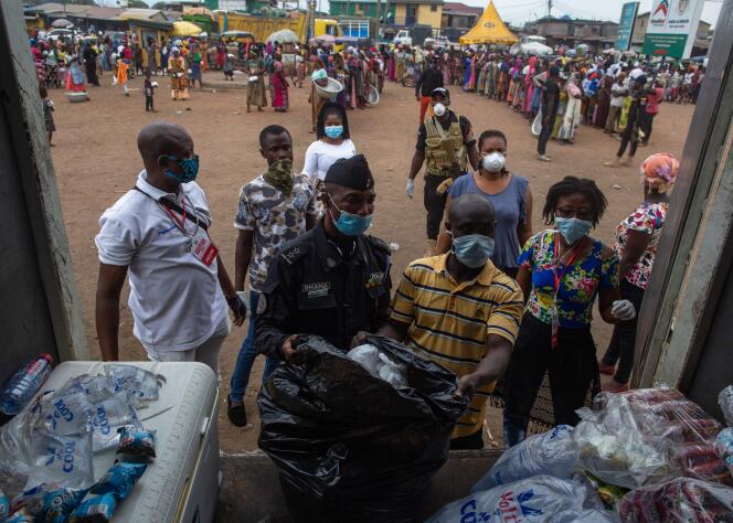 Un policier participe à la distribution de nourriture pour la population en confinement à Accra, au Ghana, le 4 avril.