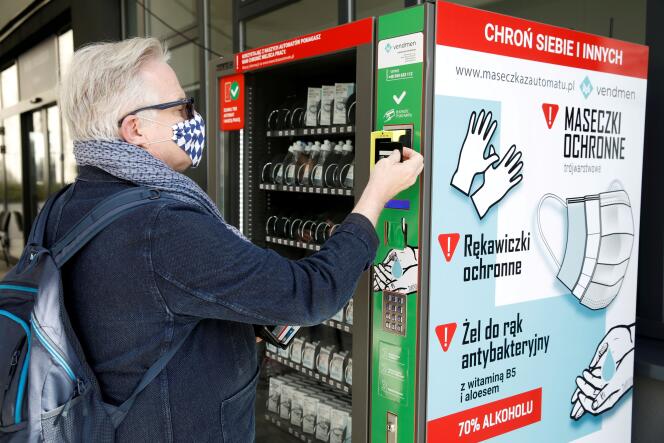 Un homme achète des gants dans un distributeur, dans une rue de Varsovie, le 10 avril.