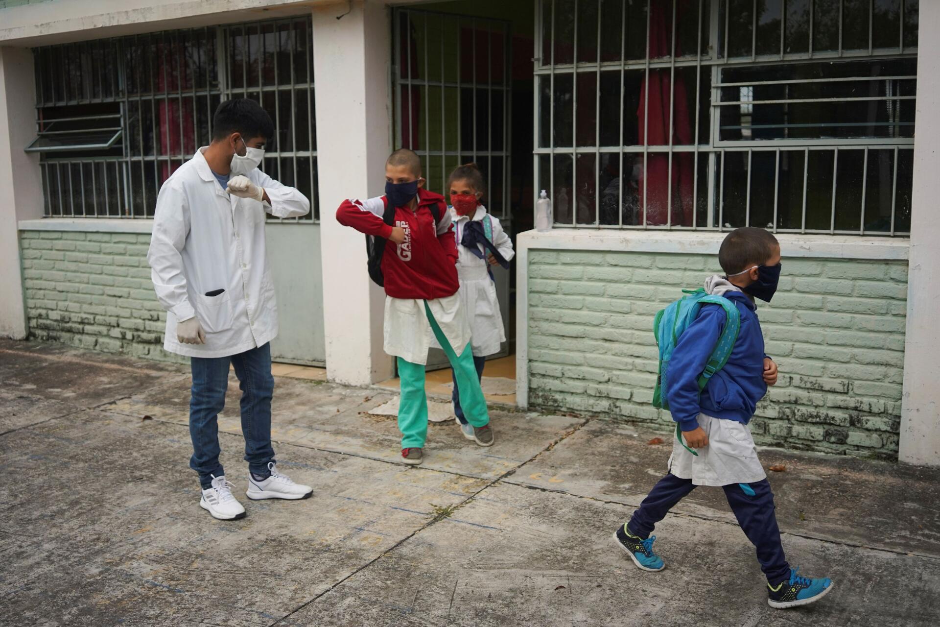 A San José, en Uruguay, le 22 avril. L’enseignant Sergio Ferrao salue du coude un de ses élèves à la fin des cours à la Escuela 30, une école rurale qui a repris ses cours après un mois de congé.