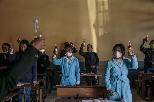 Au lycée Rabearivelo d’Antananarivo, à Madagascar, le 23 avril. Les élèves brandissent des bouteilles de Covid-Organics. Cette tisane à base d’artémisia, présentée par le gouvernement comme un puissant remède contre le coronavirus, est distribuée dans les écoles et lycées, où les enfants sont invités à en boire avant les cours.