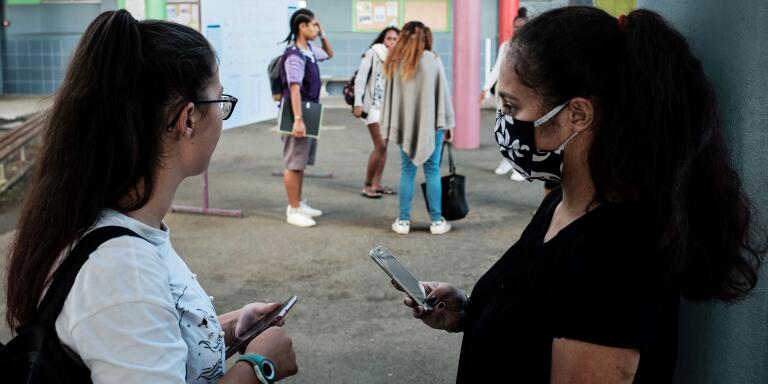 A highschool student wearing a facemask for protective measures, speaks with a friend upon their arrival at the Lycee Laperousse school, in Noumea, on the French Pacific island of New Caledonia, on April 22, 2020 on the opening day of the schools following a for weeks lockdown installed by the government to curb the spread of the COVID-19, (the novel coronavirus).  / AFP / Theo Rouby
