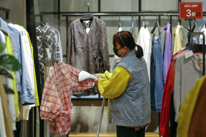 Une employée d’un magasin repasse une chemise, dans un centre commercial de Wuhan, en Chine, le 30 mars.