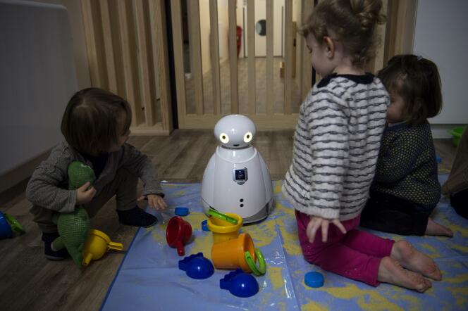 Des enfants jouent avec un robot dans une crèche, à Paris, le 1er mars 2018.