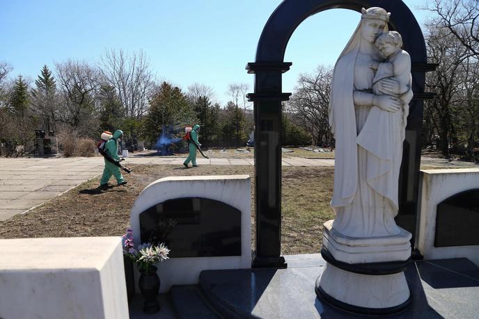 Des employés épandent de l’insecticide pour tuer les tiques dans un cimetière de Vladivostok (Russie), le 15 avril.