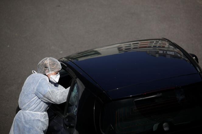 Un biologiste, vêtu d’une combinaison de protection, réalise un test de dépistage du Covid-19 sur un conducteur, à Paris, le 27 mars.
