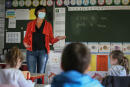 Teacher Frederique Boisyvon wearing a face mask to protect against coronavirus teaches students, in a school, in Chasne sur Illet, western France, Thursday, May 14, 2020. Authorities say over eighty percent of preschools and primary schools are reopening in France this week. (AP Photo/David Vincent)