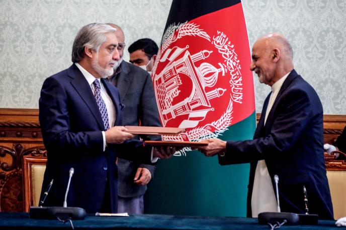 Le président afghan Ashraf Ghani (à droite) et son rival Abdullah Abdullah (à gauche) échangent des documents officiels consacrant leur accord de partage du pouvoir, le 17 mai 2020, au palais présidentiel, à Kaboul. Photographie transmise par le cabinet présidentiel.