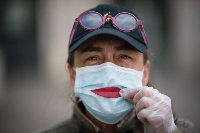 Une femme pose une feuille d’arbre sur son masque en guise de sourire, à Nantes (Loire-Atlantique), le 29 mars.