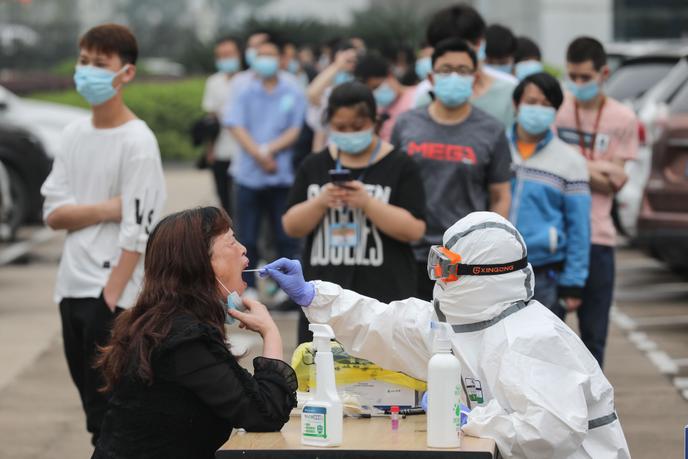 Un travailleur médical prélève un échantillon d’un employé de l’usine de moniteurs AOC pour tester le coronavirus COVID-19 à Wuhan, Chine, le 15 mai 2020.