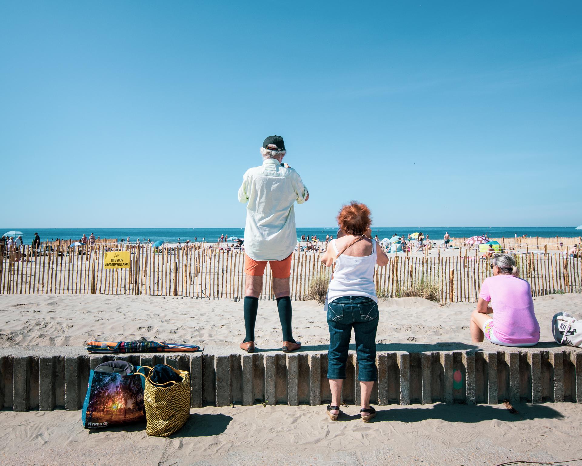 Des passants photographient la plage du Couchant le jour de sa réouverture, le 21 mai.
