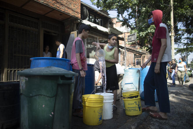 Des enfants s’approvisionnent à un réservoir d’eau mis en place par le gouvernement pendant l’épidémie, à Caracas (Venezuela), le 21 mai.