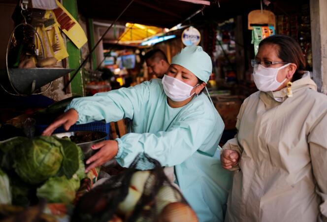 A La Paz, en Bolivie, les vendeurs des marchés portent des masques et des tenues de protection, le 20 mai.