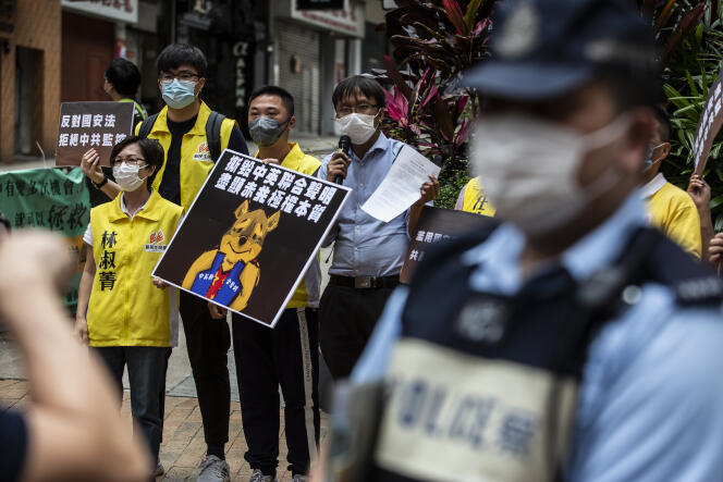 Des manifestants  tenant une pancarte de Winnie l’ourson qui représente le président chinois Xi Jinping protestant contre un nouveau projet de loi sur la sécurité, devant un poste de police à Hongkong, le 24 mai 2020.