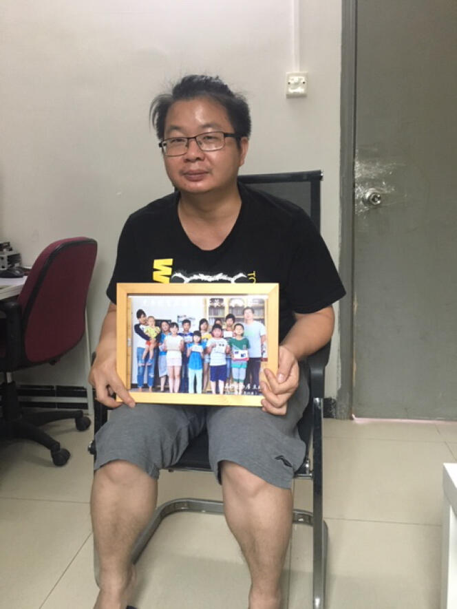 Jiang Nengjie tient dans ses mains la photo des enfants du Hunan auxquels il a consacré un documentaire, chez lui à Canton, le 16 mai.