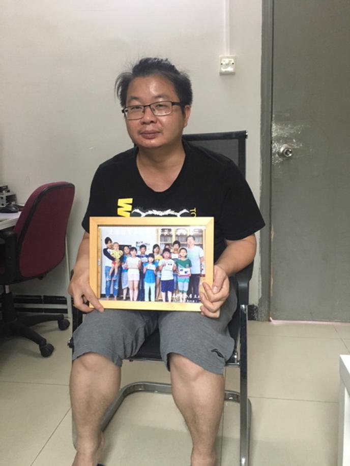 Jiang Nengjie tient dans ses mains la photo des enfants du Hunan auxquels il a consacré un documentaire, chez lui à Canton, le 16 mai.