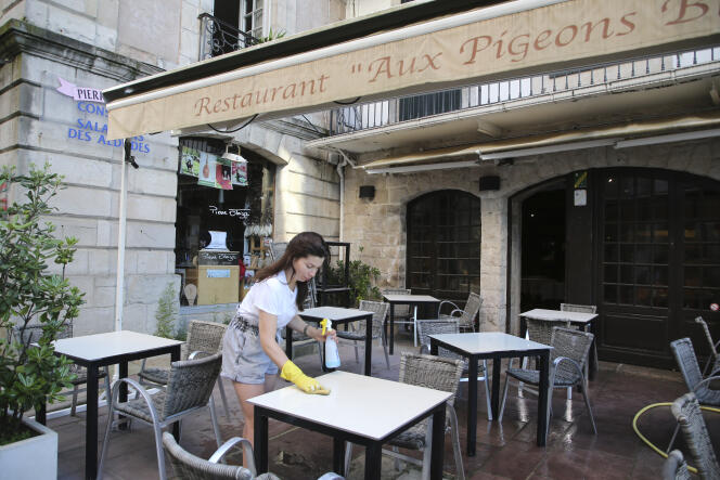 Une serveuse nettoie la terrasse d’un restaurant de Saint-Jean-de-Luz, dans les Pyrénées-Atlantiques, le 29 mai 2020, en vue de la réouverture prévue le 2 juin.