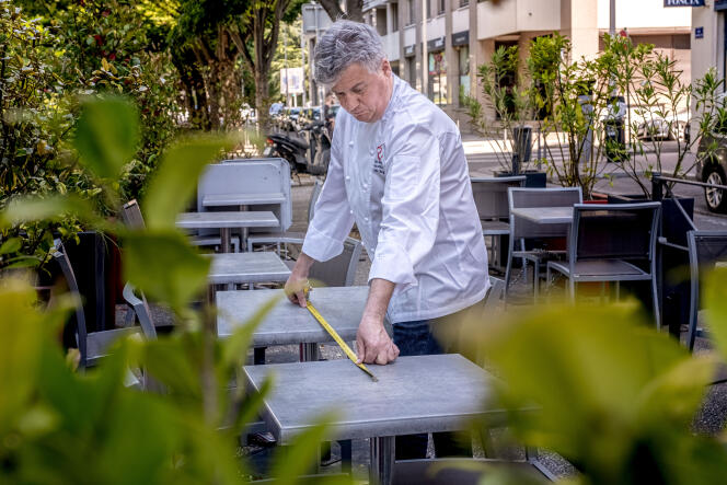 Olivier Paget, chef du restaurant L’Ame Sœur, mesure l’espacement entre les tables pour s’assurer qu’il respecte la norme, à Lyon, le 1er juin.
