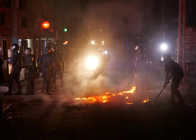 La police anti-émeute tente d’éteindre un feu lors d’une manifestation contre le couvre-feu imposé à cause de la pandémie de Covid-19, à Dakar, le 4 juin 2020.